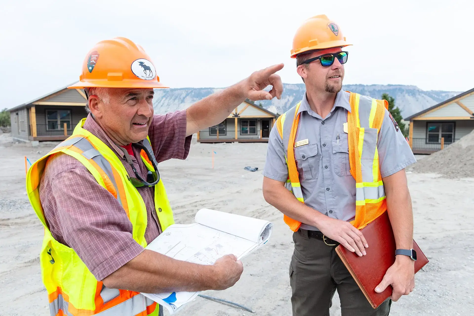 Two people in hard hats and hi-vis vests reviewing plans on a site