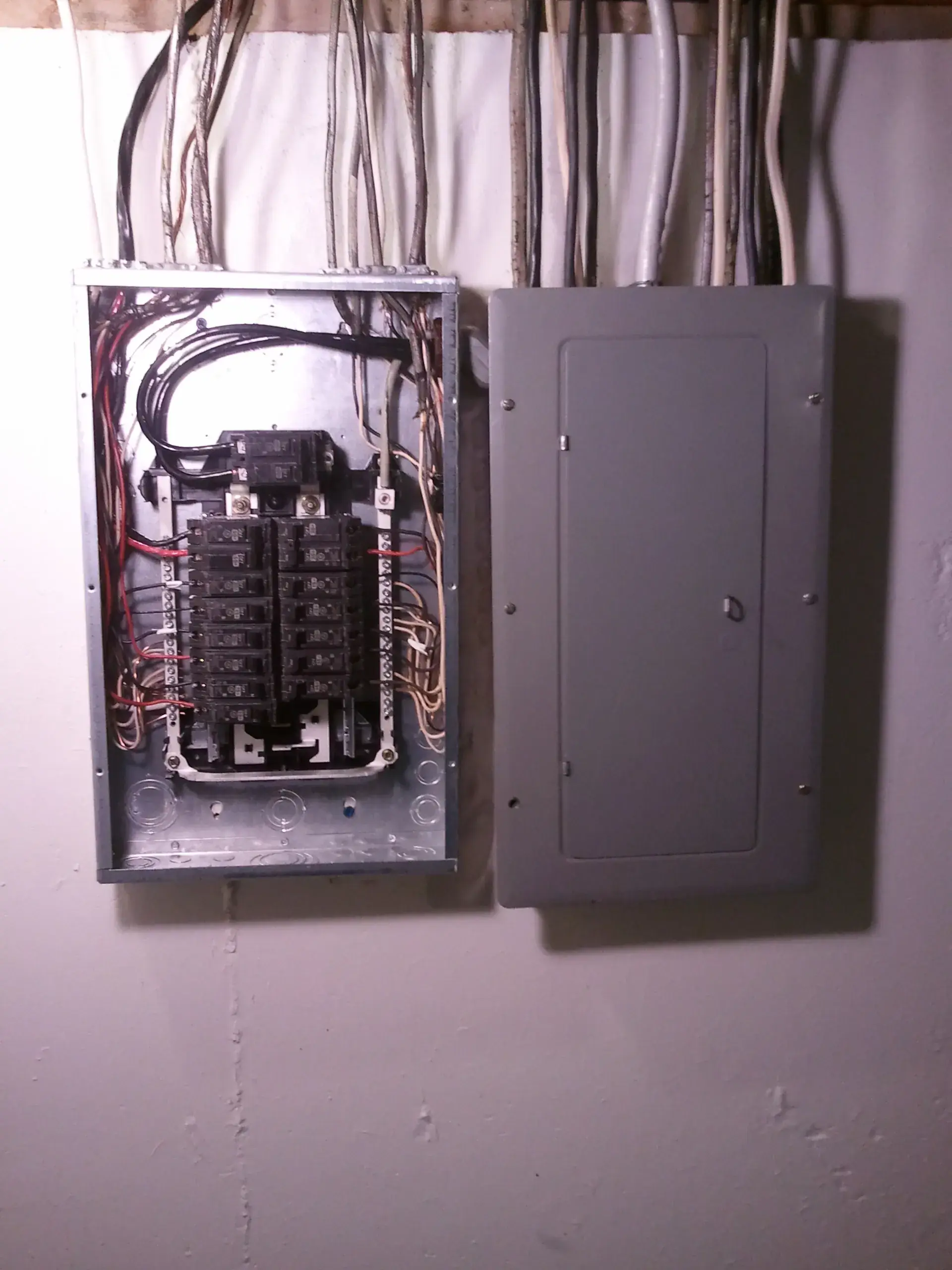 A residential electrical panel with its cover removed, breakers exposed